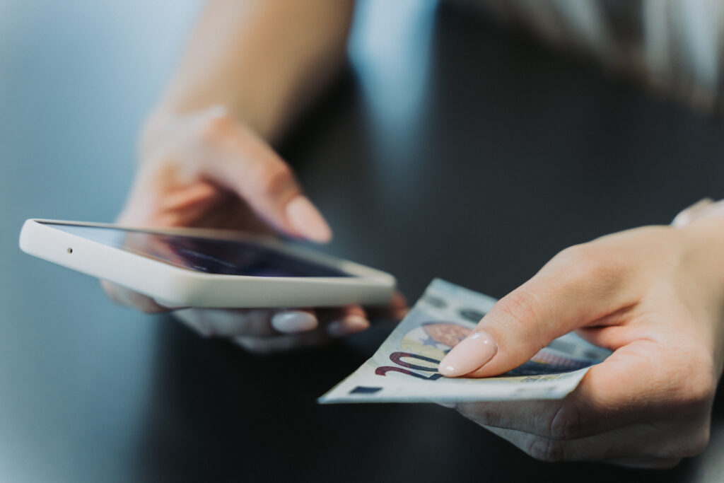 Hands holding a phone and money
